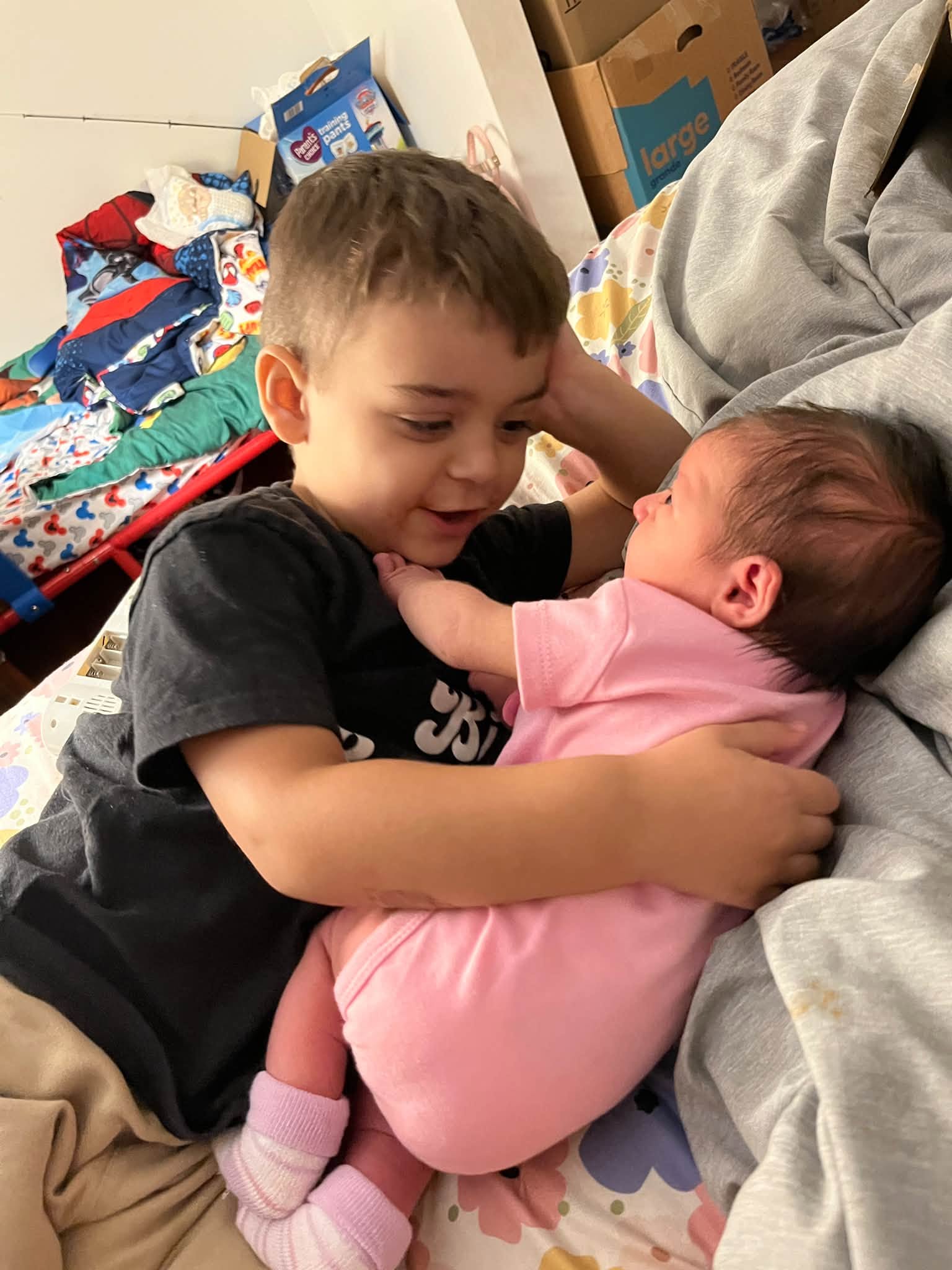 A child gently holding a newborn sibling