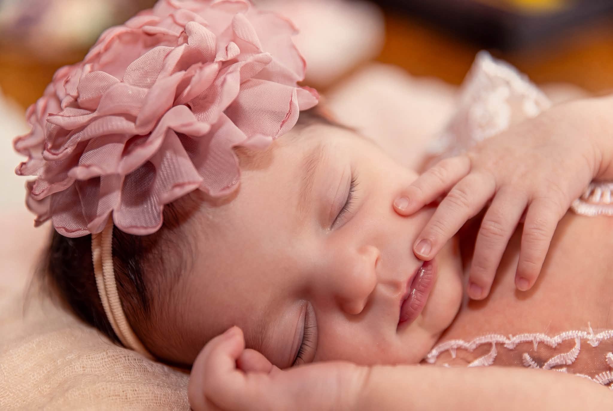 A sleeping newborn in a pink floral headband